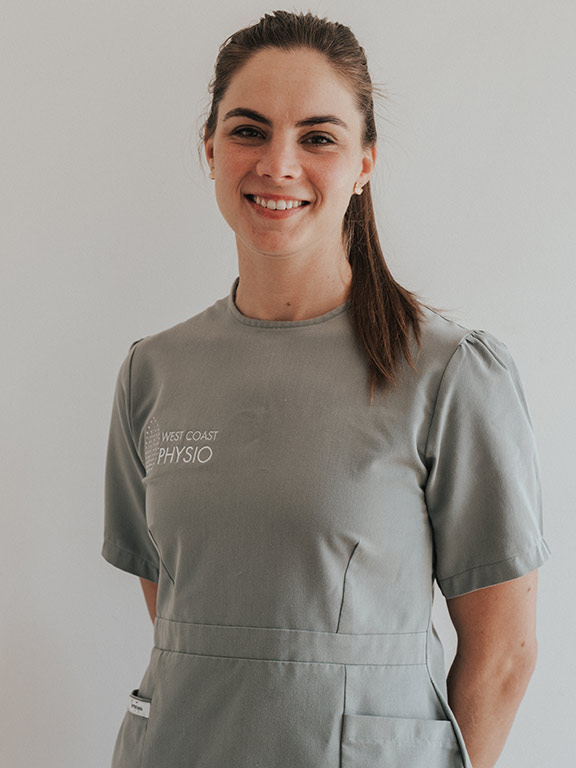Portrait of a woman in a tailored, sage-green dress uniform with 'West Coast Physio' embroidered on the left chest.